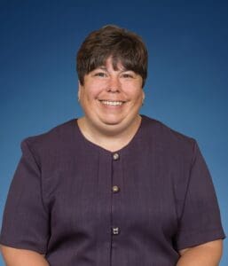 A woman in purple shirt smiling for the camera.